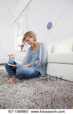 Young woman reading in her living room View Large Photo Image Stock Image - Young woman reading in her living room. Fotosearch
