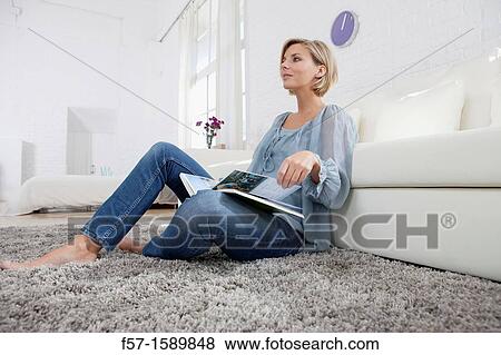 Young woman reading in her living room View Large Photo Image Stock Photo - Young woman reading in her living room. Fotosearch