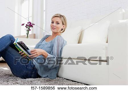 Young woman reading in her living room View Large Photo Image Stock Photograph - Young woman reading in her living room. Fotosearch