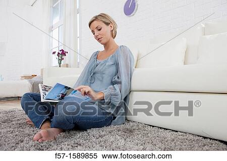Young woman reading in her living room View Large Photo Image Stock Photography - Young woman reading in her living room. Fotosearch