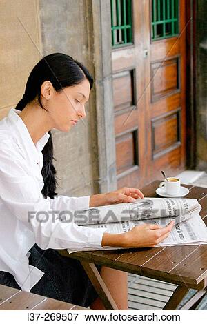 Young woman reading the newspaper at a sidewalk cafe View Large Photo Image Stock Photo - Young woman reading the newspaper at a sidewalk cafe. Fotosearch