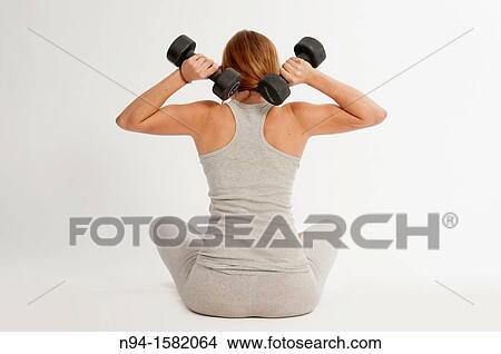 Young woman, redhead, sitting, exercising with weights at the gym View Large Photo Image Picture - Young woman, redhead, sitting, exercising with weights at the gym. Fotosearch