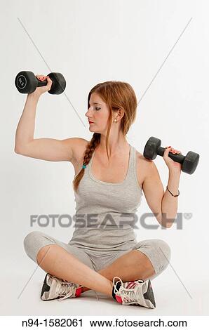 Young woman, redhead, sitting, exercising with weights at the gym View Large Photo Image Stock Image - Young woman, redhead, sitting, exercising with weights at the gym. Fotosearch