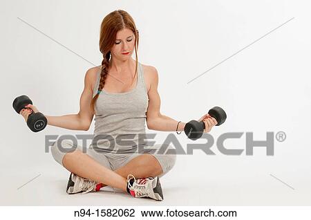 Young woman, redhead, sitting, exercising with weights at the gym View Large Photo Image Stock Image - Young woman, redhead, sitting, exercising with weights at the gym. Fotosearch