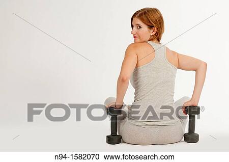 Young woman, redhead, sitting, exercising with weights at the gym View Large Photo Image Stock Image - Young woman, redhead, sitting, exercising with weights at the gym. Fotosearch