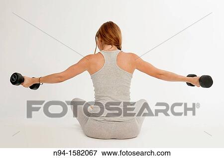Young woman, redhead, sitting, exercising with weights at the gym View Large Photo Image Stock Photo - Young woman, redhead, sitting, exercising with weights at the gym. Fotosearch