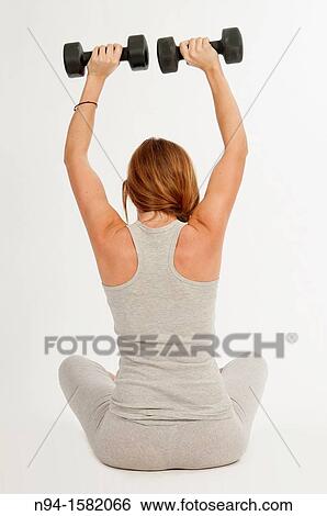 Young woman, redhead, sitting, exercising with weights at the gym View Large Photo Image Stock Photograph - Young woman, redhead, sitting, exercising with weights at the gym. Fotosearch