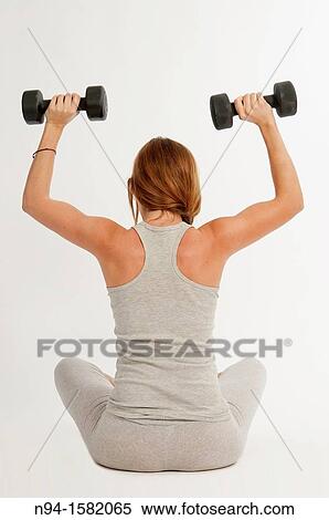 Young woman, redhead, sitting, exercising with weights at the gym View Large Photo Image Stock Photography - Young woman, redhead, sitting, exercising with weights at the gym. Fotosearch