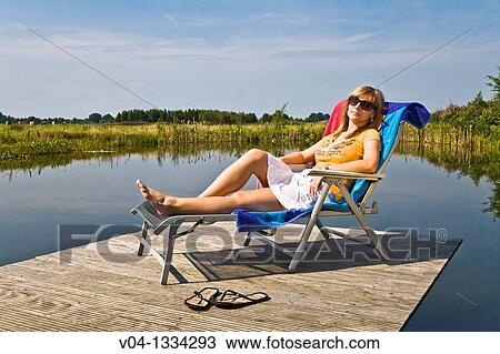 Stock Image - Young woman relaxing at a lake, Germany, Europe. Fotosearch