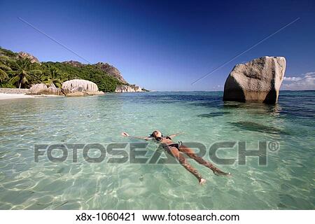 Stock Image - Young woman relaxing at Anse Source D? Argent, La Digue Island, Seychelles. Fotosearch