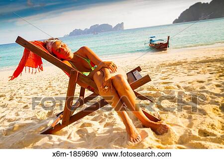 Stock Image - Young woman relaxing on a deckchair Long beach Phi Phi Don island Krabi province, Andaman Sea, Thailand. Fotosearch