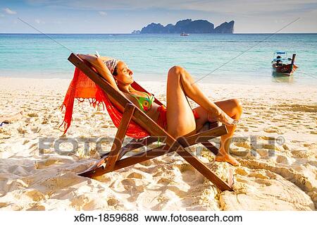 Stock Photo - Young woman relaxing on a deckchair Long beach Phi Phi Don island Krabi province, Andaman Sea, Thailand. Fotosearch