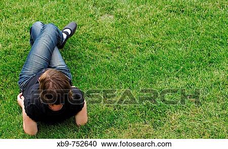 Young woman relaxing on grass View Large Photo Image Stock Image - Young woman relaxing on grass. Fotosearch