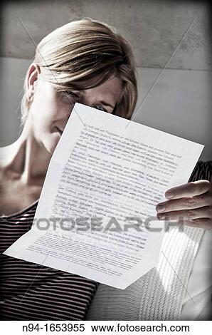 Stock Photography - Young woman relaxing, reading a personal letter to the sunlight coming through the bedroom window.. Fotosearch