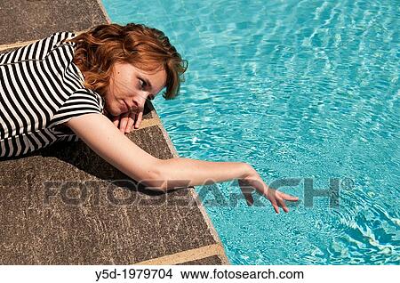 young woman resting at the poolside, touching water View Large Photo Image Picture - young woman resting at the poolside, touching water. Fotosearch