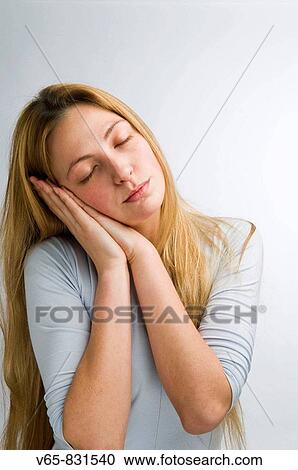 young woman resting her head in her hands as if about to go to sleep View Large Photo Image Stock Image - young woman resting her head in her hands as if about to go to sleep. Fotosearch