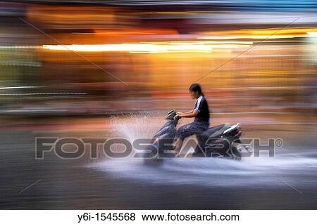 Young woman rides motor scooter at speed in rain along flooded De Tham Street Pham Ngu Lao district Ho Chi Minh City Vietnam View Large Photo Image Stock Photo - Young woman rides motor scooter at speed in rain along flooded De Tham Street Pham Ngu Lao district Ho Chi Minh City Vietnam. Fotosearch