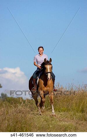 Young woman riding horse in a field View Large Photo Image Stock Photograph - Young woman riding horse in a field. Fotosearch