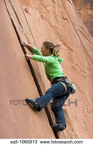 Stock Image - Young woman rock climbing off Utah Scenic Byway 279 near Moab, Utah, USA. Fotosearch