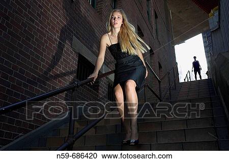 Young woman rushing down urban stairway with a sense of fear as a man follows her View Large Photo Image Stock Image - Young woman rushing down urban stairway with a sense of fear as a man follows her. Fotosearch