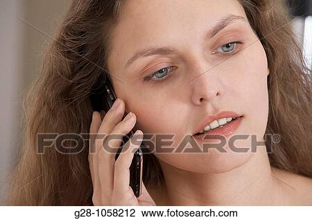 Stock Image - young woman? s hands holding a telephone and looking serious. Fotosearch