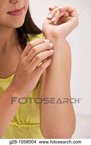 Picture - Young woman scratching her wrist. Fotosearch