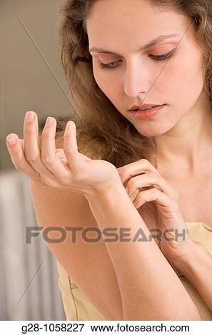 Stock Photo - young woman scratching the inside of her wrist because of an itching sensation. Fotosearch