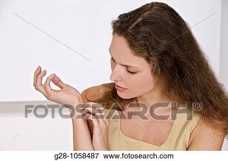 Stock Photo - young woman scratching the inside of her wrist because of an itching sensation. Fotosearch