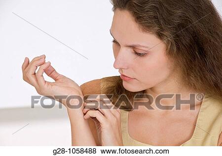 young woman scratching the inside of her wrist because of an itching sensation View Large Photo Image Stock Photo - young woman scratching the inside of her wrist because of an itching sensation. Fotosearch