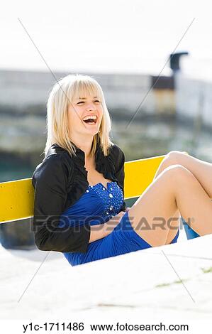 Stock Photograph - Young woman seated is laughing. Fotosearch