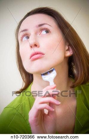 Stock Photograph - Young woman shaving her face.. Fotosearch