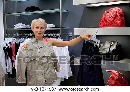 Young woman shopping and comparing different clothes in store View Large Photo Image Stock Photo - Young woman shopping and comparing different clothes in store. Fotosearch