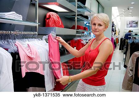 Young woman shopping and comparing different clothes in store View Large Photo Image Stock Photography - Young woman shopping and comparing different clothes in store. Fotosearch