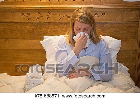 Stock Image - Young woman sick in bed. Fotosearch