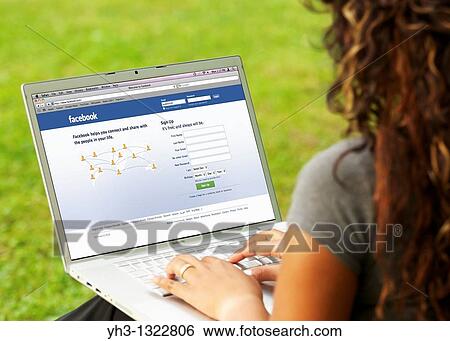 Young woman signing in on her Facebook page online on a laptop alone at the park View Large Photo Image Stock Photograph - Young woman signing in on her Facebook page online on a laptop alone at the park. Fotosearch