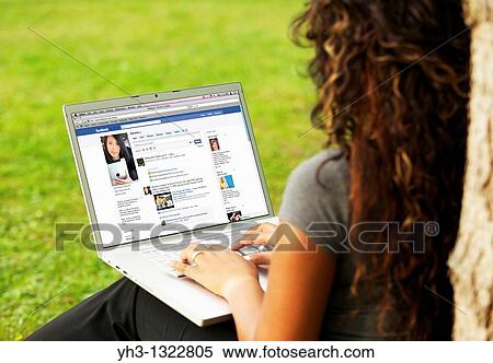 Young woman signing in on her Facebook page online on a laptop alone at the park View Large Photo Image Stock Photography - Young woman signing in on her Facebook page online on a laptop alone at the park. Fotosearch