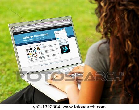 Young woman signing in on her Twitter page online on a laptop alone at the park View Large Photo Image Picture - Young woman signing in on her Twitter page online on a laptop alone at the park. Fotosearch