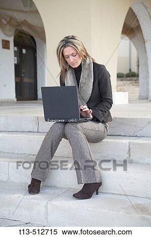 Young woman sitting and using laptop computer View Large Photo Image Stock Photography - Young woman sitting and using laptop computer. Fotosearch