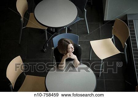 Young woman sitting at a table in a cafeteria. View Large Photo Image Stock Photo - Young woman sitting at a table in a cafeteria.. Fotosearch