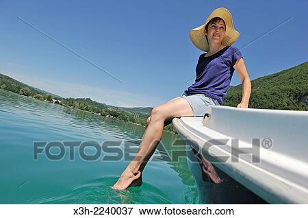 Stock Photo - young woman sitting at the prow of a small boat powered with electric motor on the natural Lake of Aiguebelette, department of Savoie, Rhone-Alpes region, France, Europe.. Fotosearch