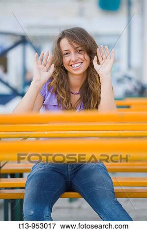 Young woman sitting behind Orange table acting? hands up? View Large Photo Image Stock Photo - Young woman sitting behind Orange table acting? hands up?. Fotosearch