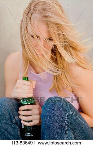 Young woman sitting drunk with a beer in her hands View Large Photo Image Stock Image - Young woman sitting drunk with a beer in her hands. Fotosearch