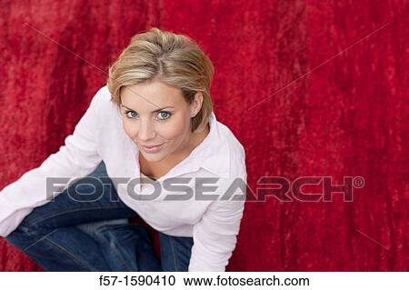 Young woman sitting in the yoga position on a red carpet View Large Photo Image Stock Image - Young woman sitting in the yoga position on a red carpet. Fotosearch