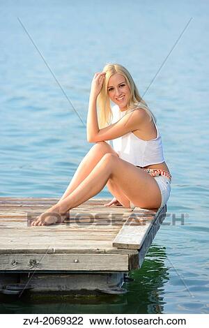 Young woman sitting on a jetty at a lake in Austria. View Large Photo Image Stock Image - Young woman sitting on a jetty at a lake in Austria.. Fotosearch