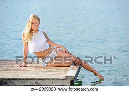 Young woman sitting on a jetty at a lake in Austria. View Large Photo Image Stock Image - Young woman sitting on a jetty at a lake in Austria.. Fotosearch
