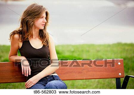 Young woman sitting on bench View Large Photo Image Stock Image - Young woman sitting on bench. Fotosearch