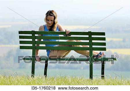 Stock Photo - Young woman sitting on bench. Fotosearch