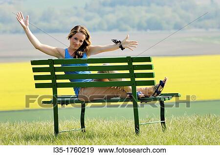 Young woman sitting on bench View Large Photo Image Stock Photo - Young woman sitting on bench. Fotosearch
