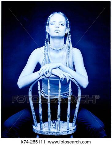 Stock Image - Young Woman Sitting On Chair Smoking. Fotosearch