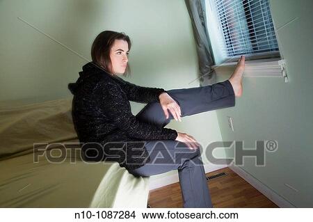 Picture - Young woman sitting on her bed. Fotosearch